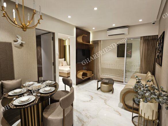 A luxurious, modern living room in a 1BHK apartment at JP North by JP Infra, featuring elegant interiors, a cozy dining area, a stylish chandelier, and a balcony with natural light.