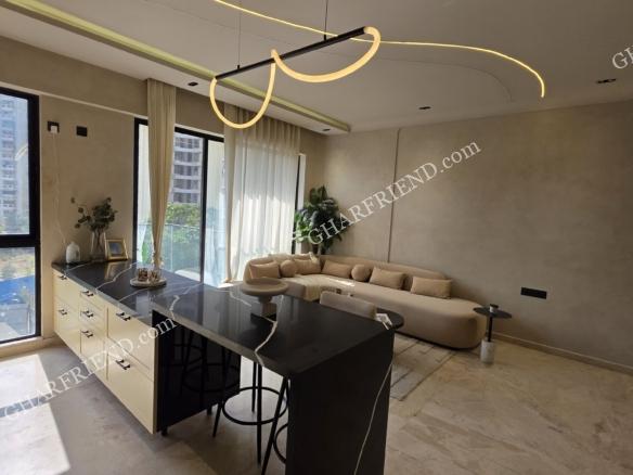 Luxury 1 BHK apartment interior at Kanungo Beaumonde in Mira Road featuring modular kitchen, sunlit living area, and full-height glass windows